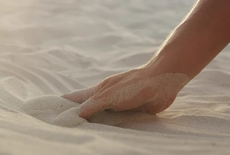 Hand auf feinem Sand, sanftes Tageslicht